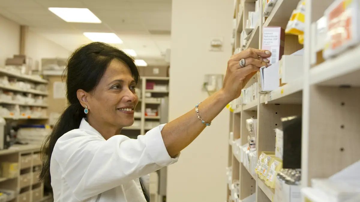 A pharmacist taking a box of medicine from a shelf